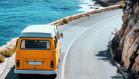 gelber Bus fährt Straße am Meer entlang