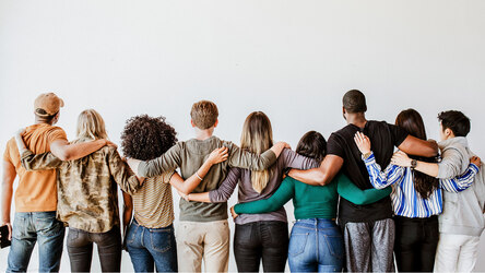 Mehrere Menschen sind von hinten zu sehen, stehen nebeneinander und legen Arme um sich