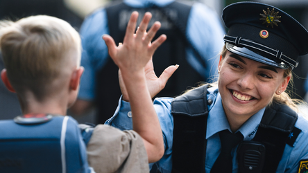 fröhliche Polizistin klatscht sich mit einem Schulanfänger ab