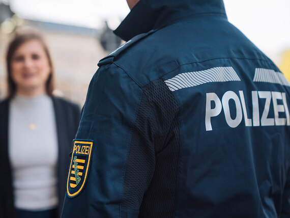 Ein Bürgerpolizist im Gespräch mit einer jungen Frau. Der Bürgerpolizist ist als Polizeibeamter Ansprechpartner für die Menschen vor Ort.