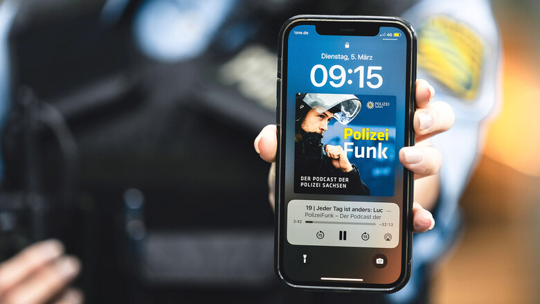 Auf einem Smartphone in der Hand einer Polizeibeamtin ist das Logo des Polizei-Podcasts »PolizeiFunk« zu sehen.