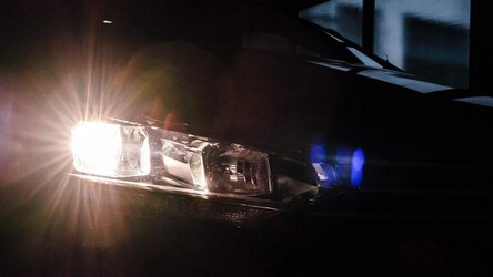 Der Scheinwerfer eines Autos mit einer Lichtreflexion in einer dunkler Garage.
