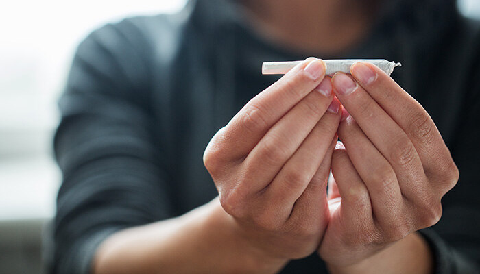 Junger Mensch hält Joint