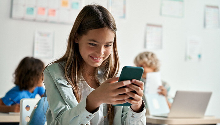 Mädchen schaut glücklich auf Smartphone