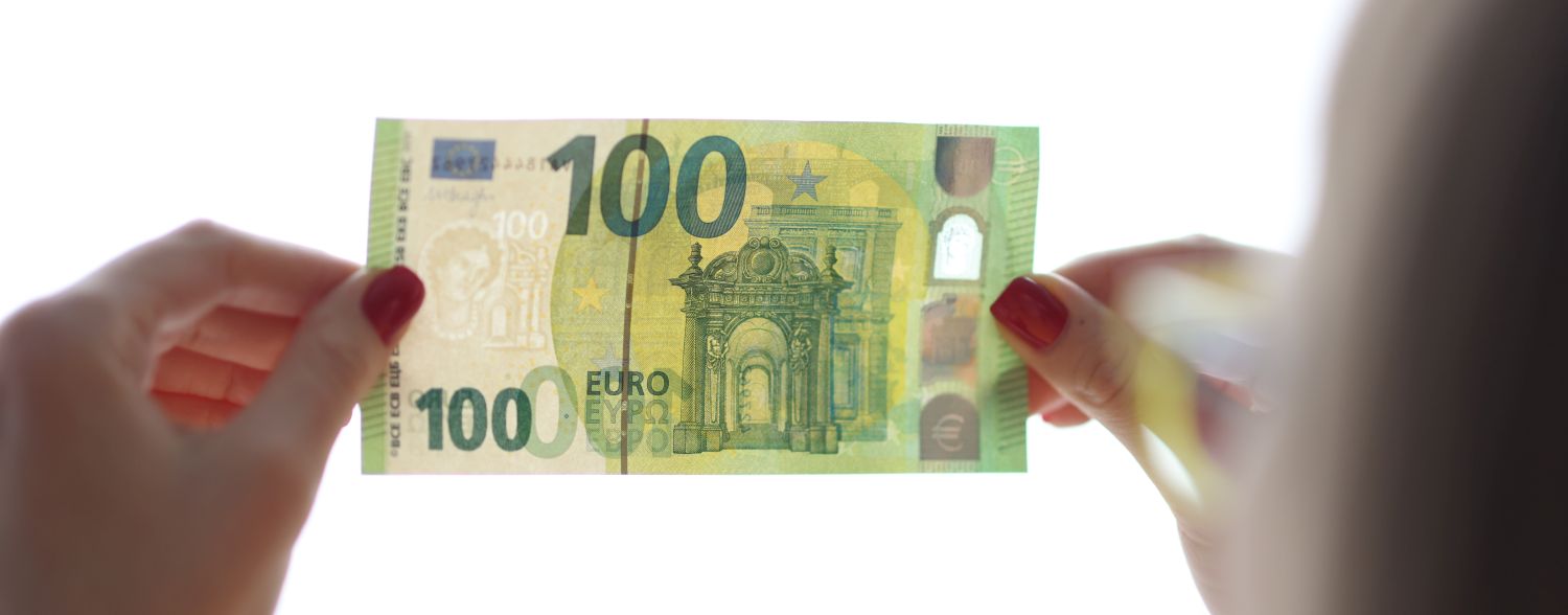 Frau hält 100-Euro-Banknote gegen das Licht