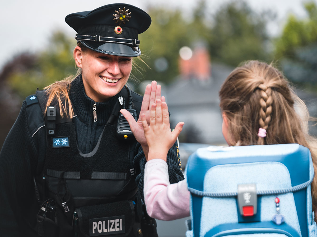 Polizistin klatscht mit Schülerin ab.