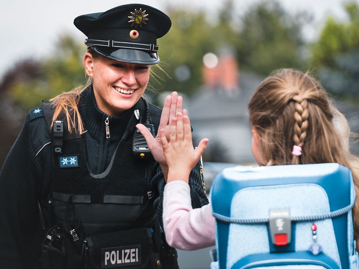 Polizistin klatscht mit Kind ab.