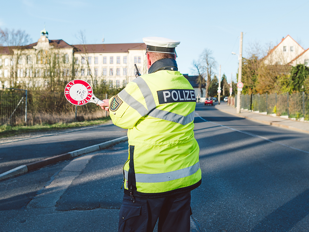 Polizist mit Kelle steht auf Straße