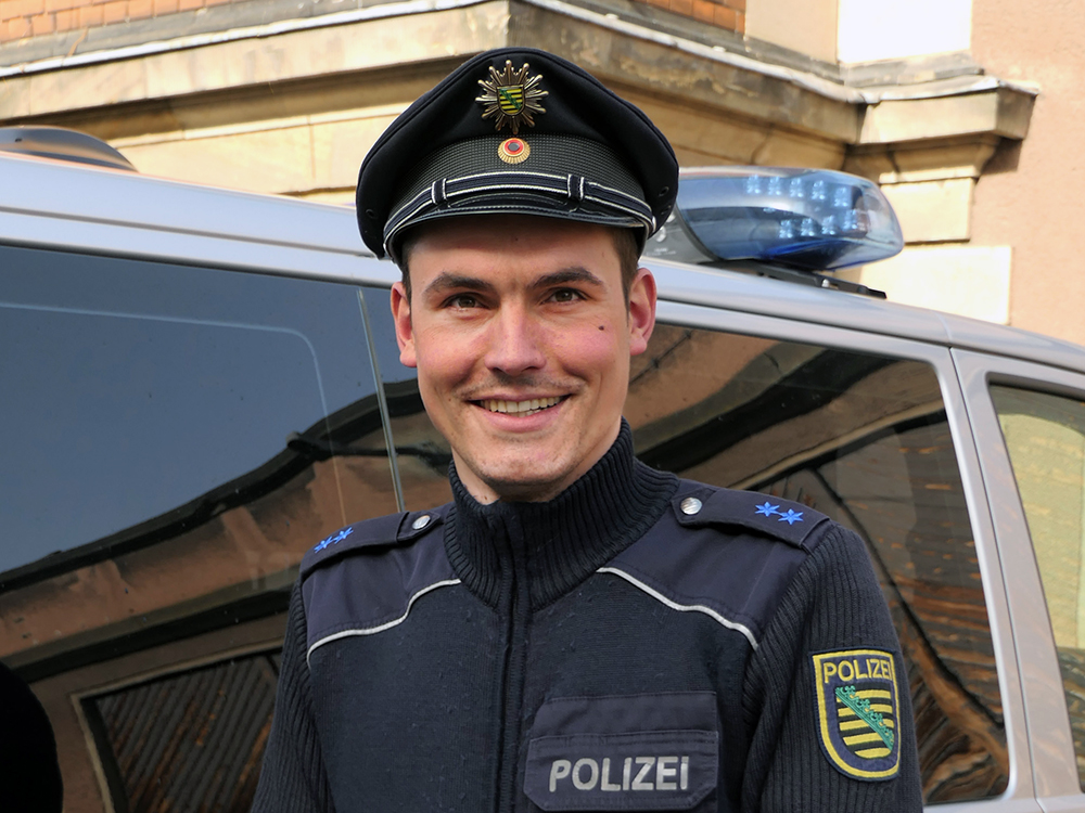 Polizist Florian steht vor einem Auto