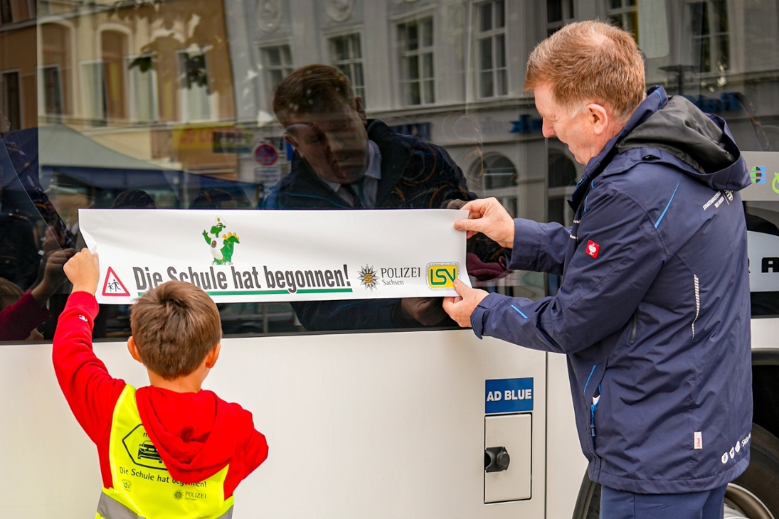 Dr. Pfeil bringt mit einen Jungen Aufkleber an.