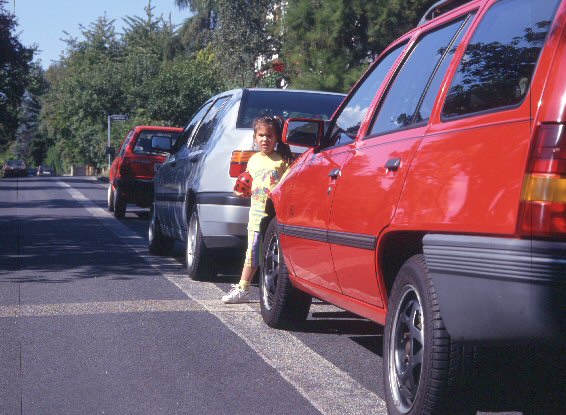 Kind steht zwischen Auto