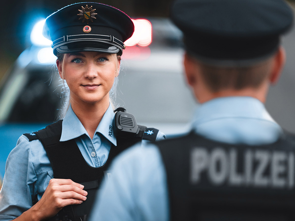 Eine Polizistin vor einem Streifenwagen.