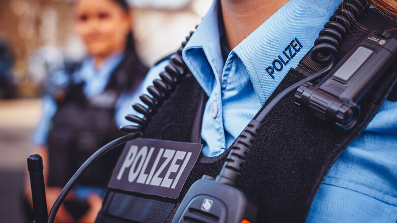 Detail einer Polizei-Uniform: Auf der Weste sowie am Kragen ist gut sichtbar der Schriftzug »Polizei« an der Kleidung einer Beamtin zu sehen.