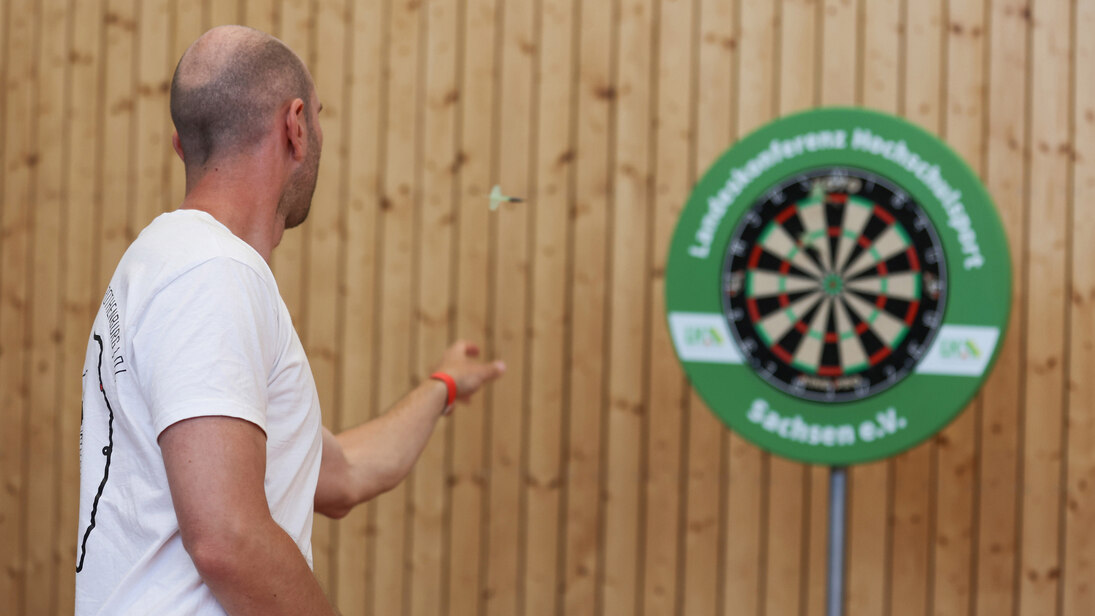 Person wirft den Pfeil auf die Dartscheibe