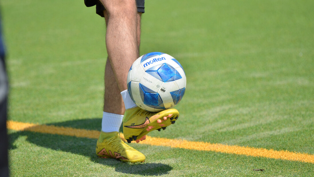 Person balanciert einen Fußball auf dem Fuß
